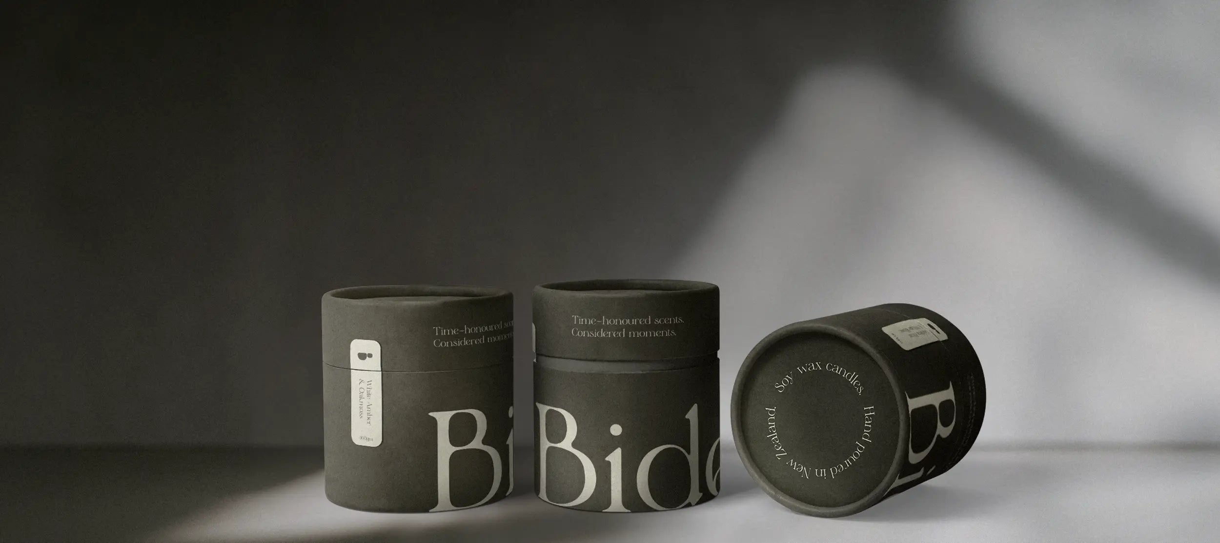 Bide candle packaging arrange on grey background with natural light casting across the scene