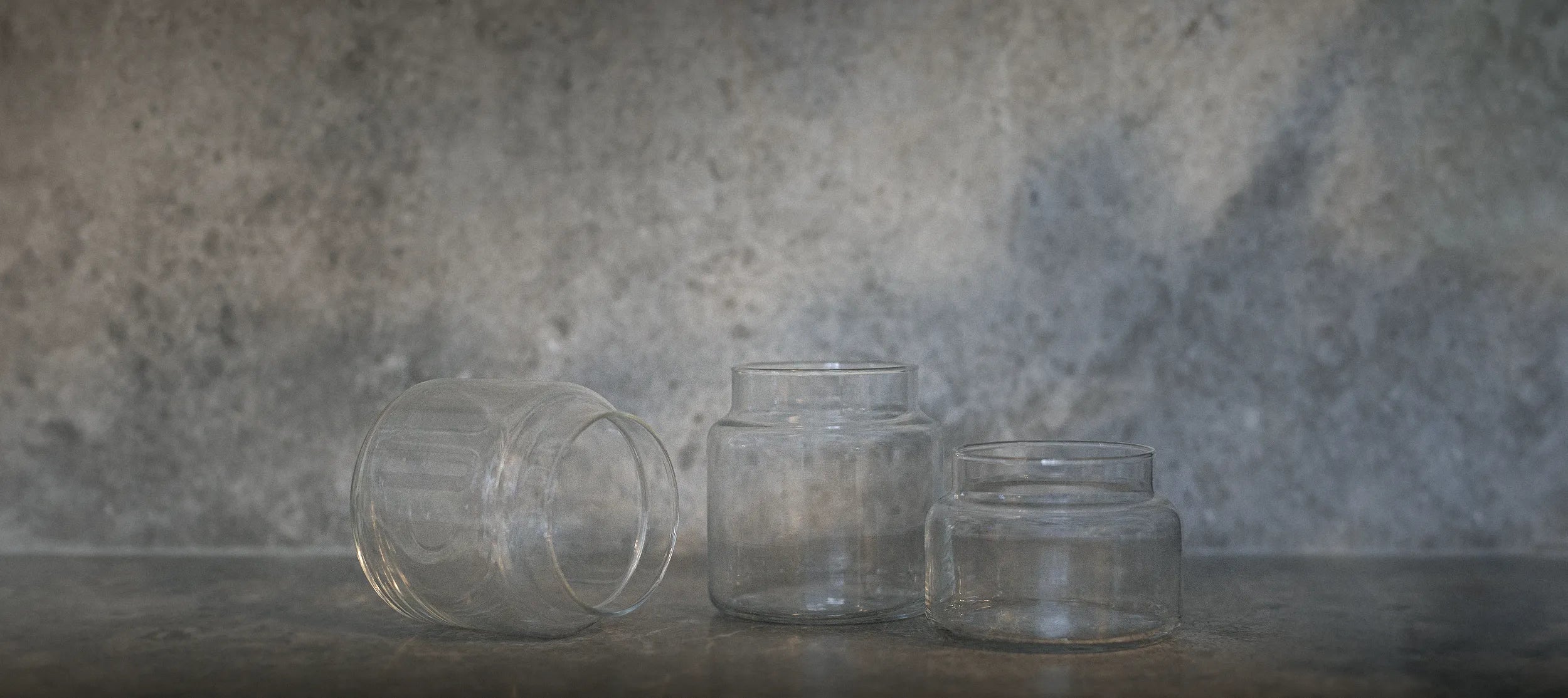 Three empty Bide candle jars on a marble background with natural light casting across the scene