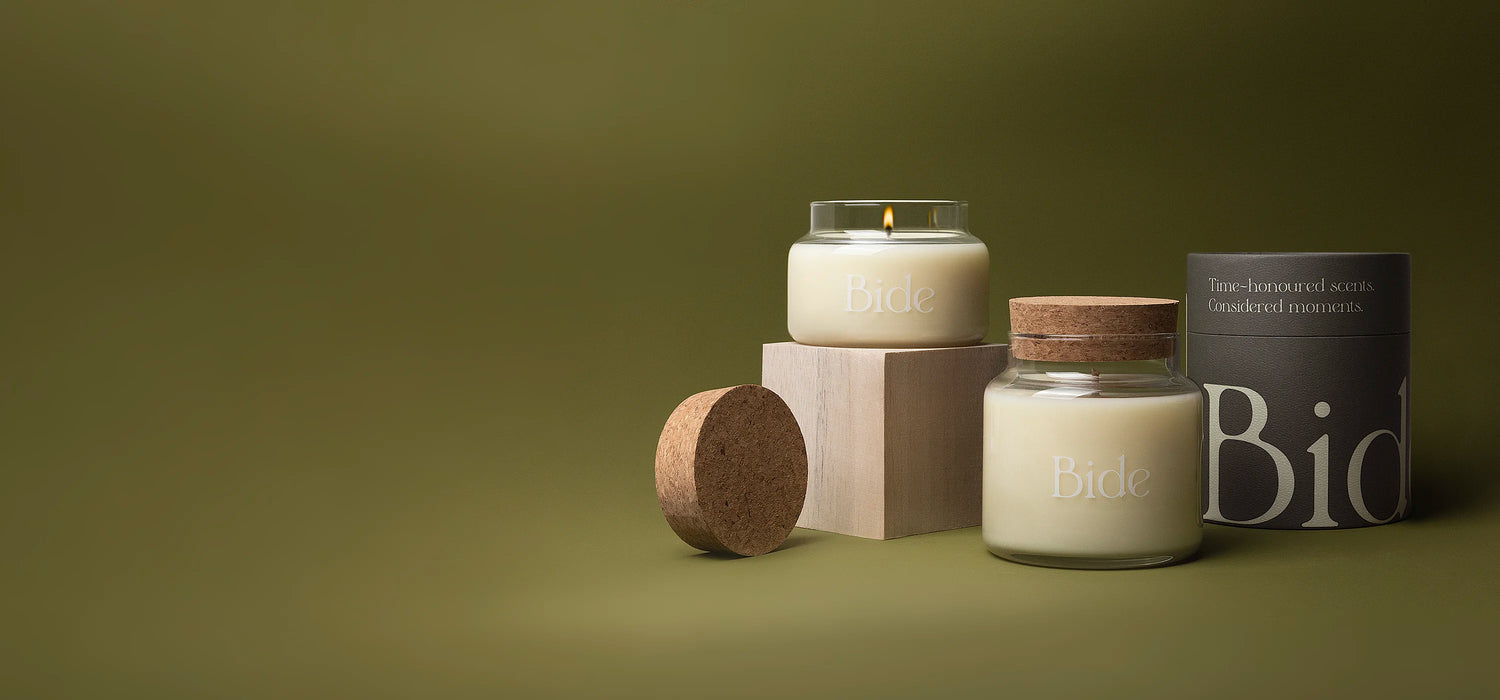 Small and large Bide candles arranged on olive green background with some packaging elements